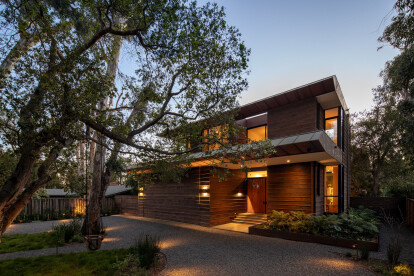 At the front of the home, one is greeted by the California live oak and Eucalyptus trees that define the local landscape and keep in proportion with the generous home, while the airplane hangar style garage door.