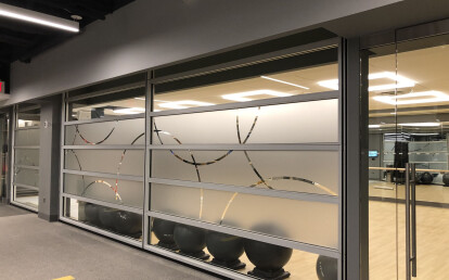 Custom Skyfold Mirage with frosted etched and clear glass panels sub-dividing an office gym