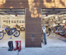 The workshop opens out onto a protected exterior work yard. The bright interiors stand out against the corrugated corten steel façade.