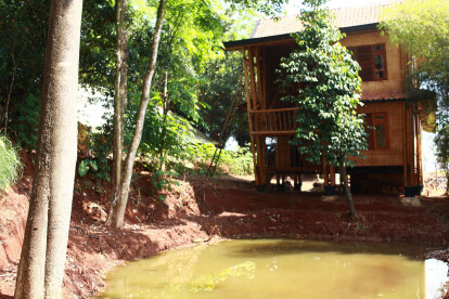 Two-storied bamboo house is placed next to a pond