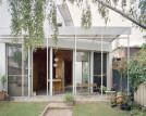 Glazed sliding doors open to the rear garden and to the courtyard, creating a large, connected indoor/outdoor space bookended by greenery.