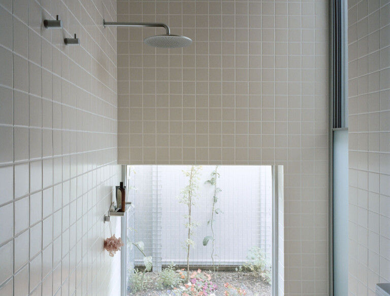 A low, fixed window in the downstairs bathroom spills light from a small courtyard into the shower, while maintaining privacy.