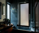 The bathroom features a raw edge vanity with a soapstone shower outfitted with bespoke hardware from Czech and Speake