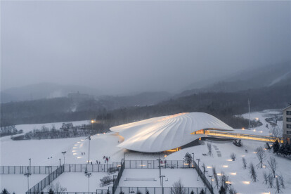 MAD nestles Yabuli Congress Center in snowy mountainous terrain covered by a rippling curved roof