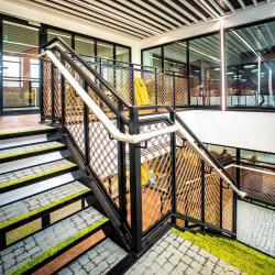 Wire mesh railing infill panels surround the main stairs and balcony of Norfolk County Hall.