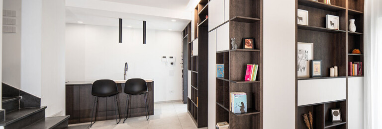 Custom made wooden wall detail; which embraces a long portion of the living area and becomes the protagonist of the space, on the right the kitchen area with central island