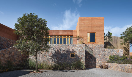 View of rammed earth dwelling and community spaces linked by stone and gravel courtyards