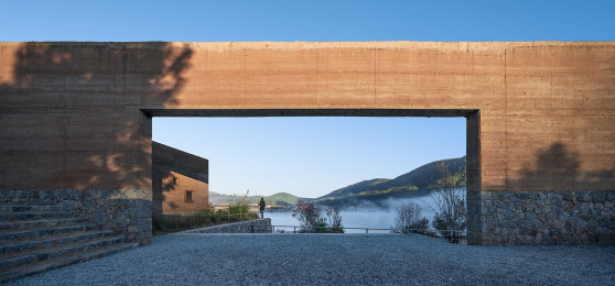 Entry to west campus streets and courtyards network with stone and rammed earth walls framing curated views of landscape