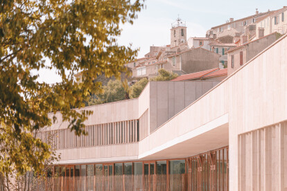 Amelia Tavella Architectes completes an elongated school of stone fitted to the contours of its hillside site