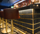 Sophistication at the bar: Rich leather stools line up in perfect symmetry, complemented by the golden glow of sleek accents, inviting a moment of luxury with every sip.