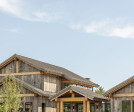 Rustic lodge vibes, covered front entry, exterior design. Reclaimed wood siding, corrugated metal roofs. Sustainable, natural materials, biophilic design.