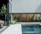 The pool occupies the central courtyard and connects to the entertaining space and guesthouse through full-height sliding doors.